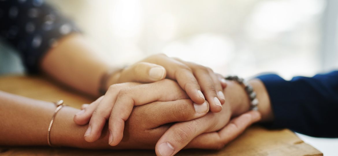 a close up of a pair of hands clasping another pair of hands in comfort